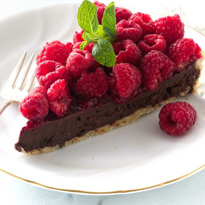 A slice of a chocolate raspberry tart on a dessert plate.