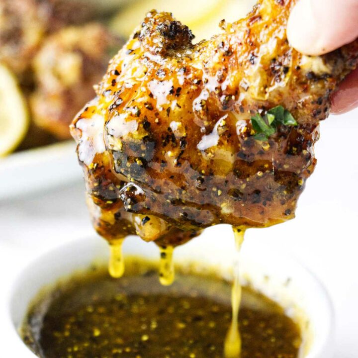 A honey lemon pepper chicken wing being dipped in sauce.