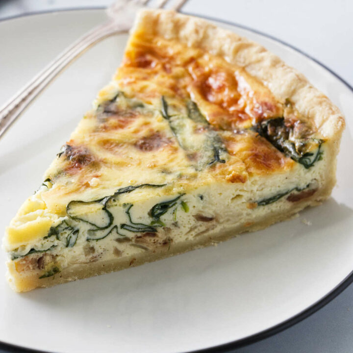 A slice of quiche florentine on a dinner plate.