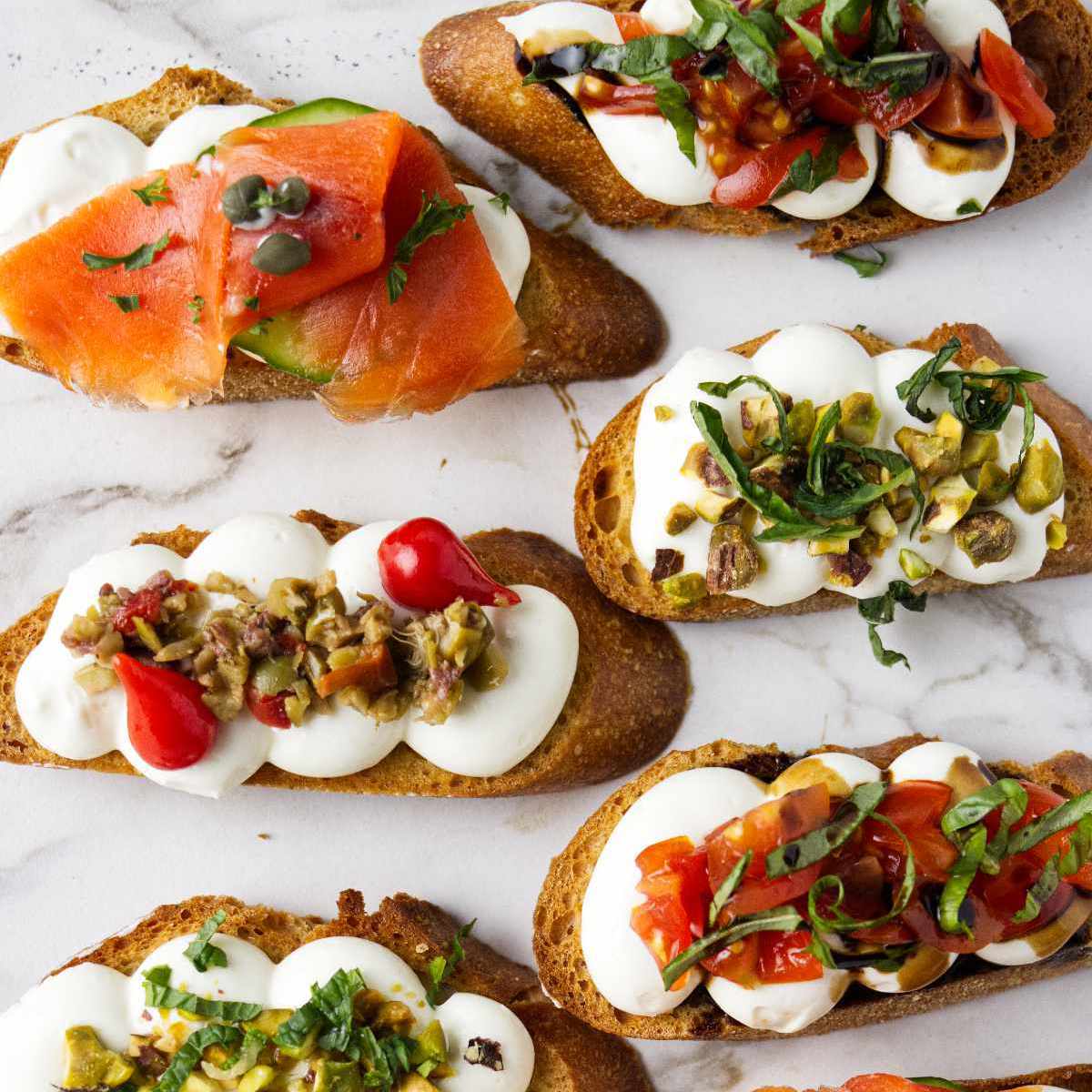 Whipped ricotta crostini topped with smoked salmon, tomatoes and basil, and olive tapenade.