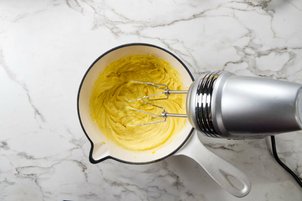 Using a mixer to cream butter, sugar, and egg yolks.