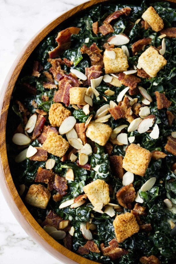 A large bowl of kale salad with croutons on top.