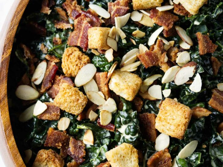 A large bowl of kale salad with croutons on top.