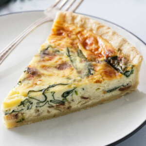 A slice of quiche with spinach baked into the center of the quiche.
