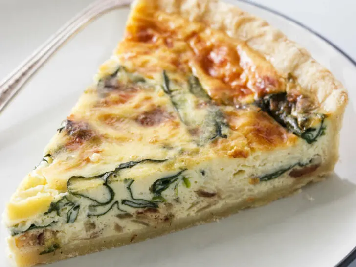 A slice of quiche with spinach baked into the center of the quiche.