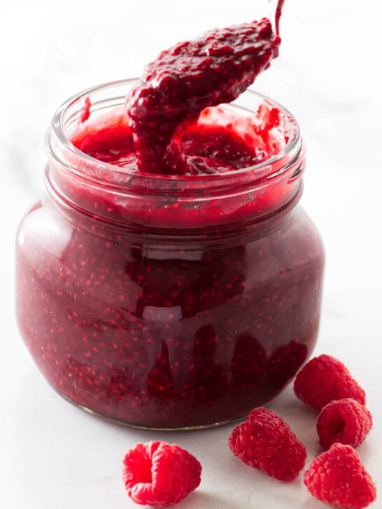 Scooping raspberry sauce out of a jar.