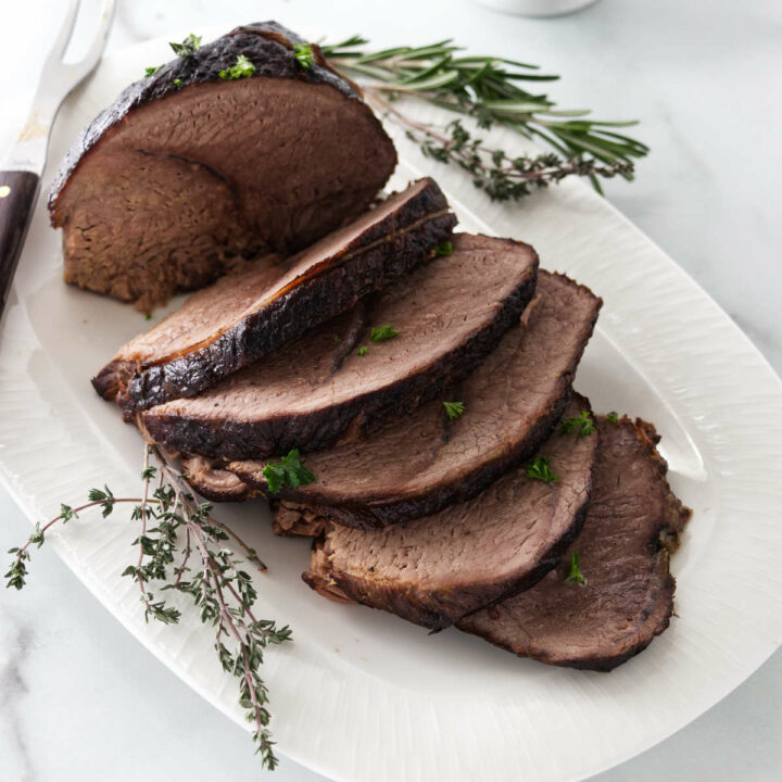 A sirloin tip roast sliced and placed on a serving dish.