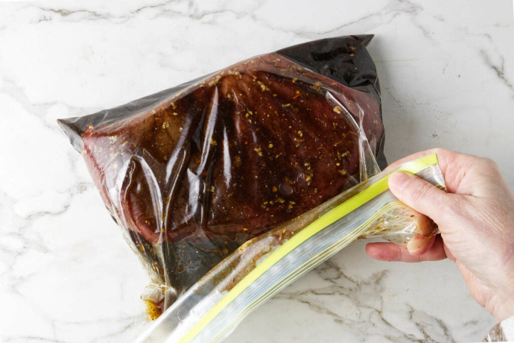 Sealing meat in a closable bag with marinade.