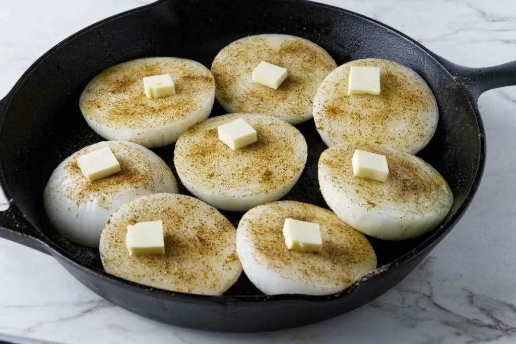 Dollops of butter on top of onions in a skillet.