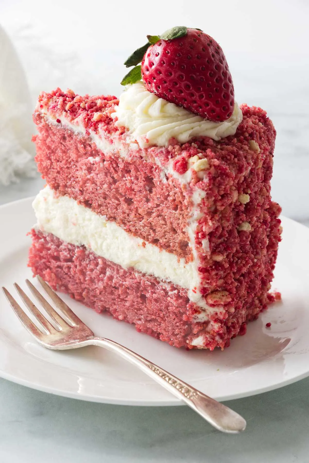 A slice of a strawberry cake coated with strawberry crunch crumble.