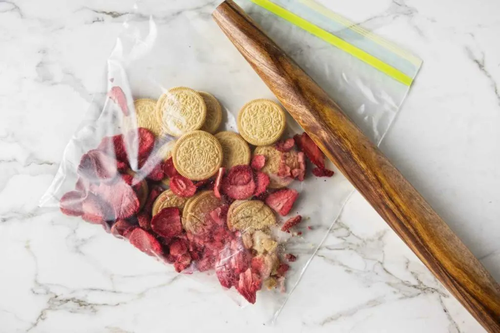 Crushing oreos and freeze dried strawberries in a plastic bag.