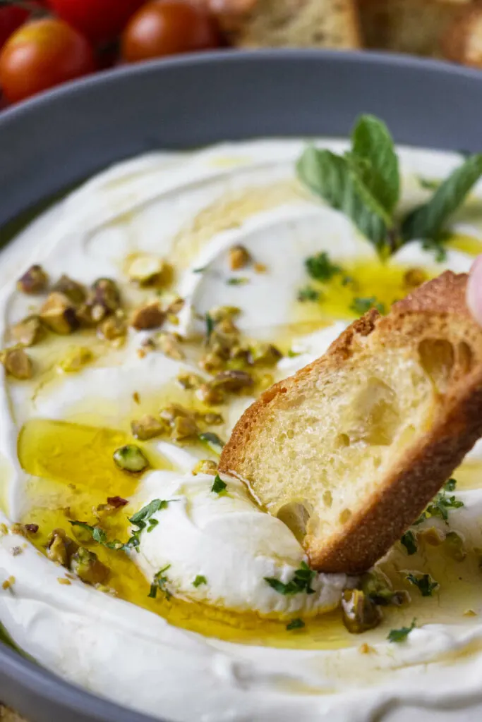 Dipping toast in whipped ricotta.