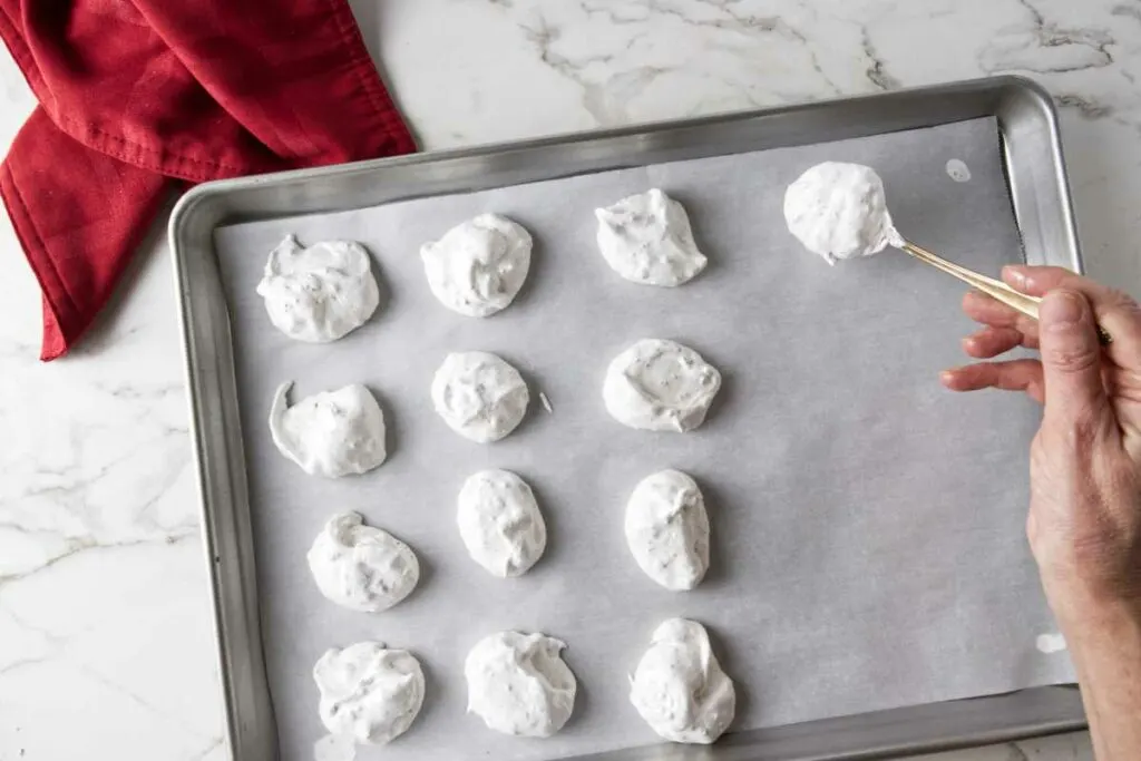 Spooning mounds of meringue on a cookie sheet.