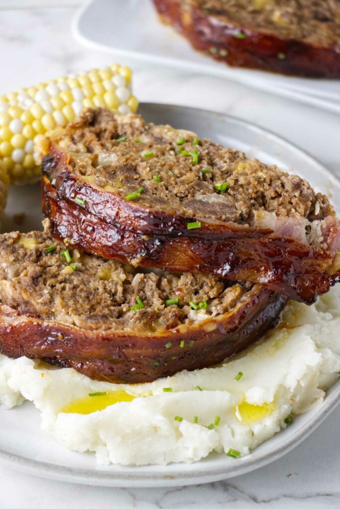 Two slices of meatloaf on a plate with mashed potatoes.