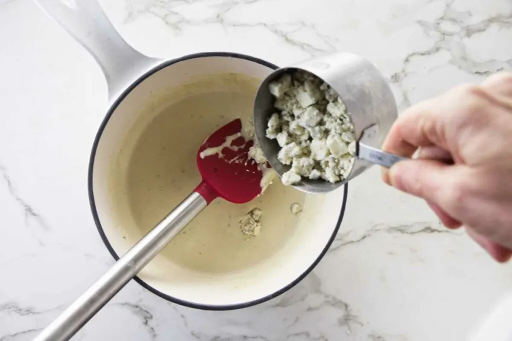 Adding blue cheese crumbles to the sauce.