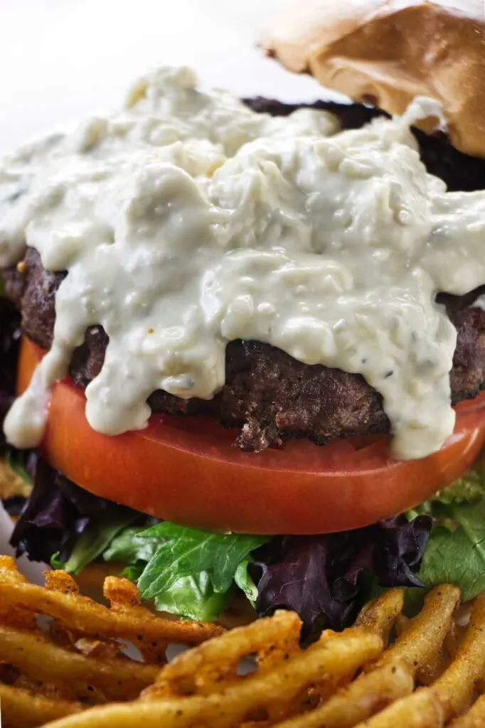 Blue cheese sauce drizzling down a burger.