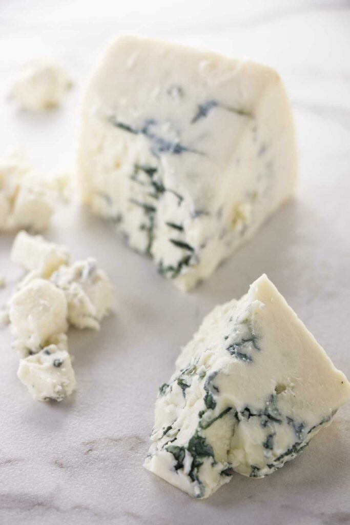 A block of blue cheese is broken in half.