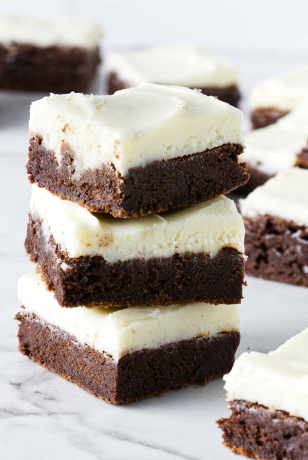 A stack of brownies with cream cheese frosting.