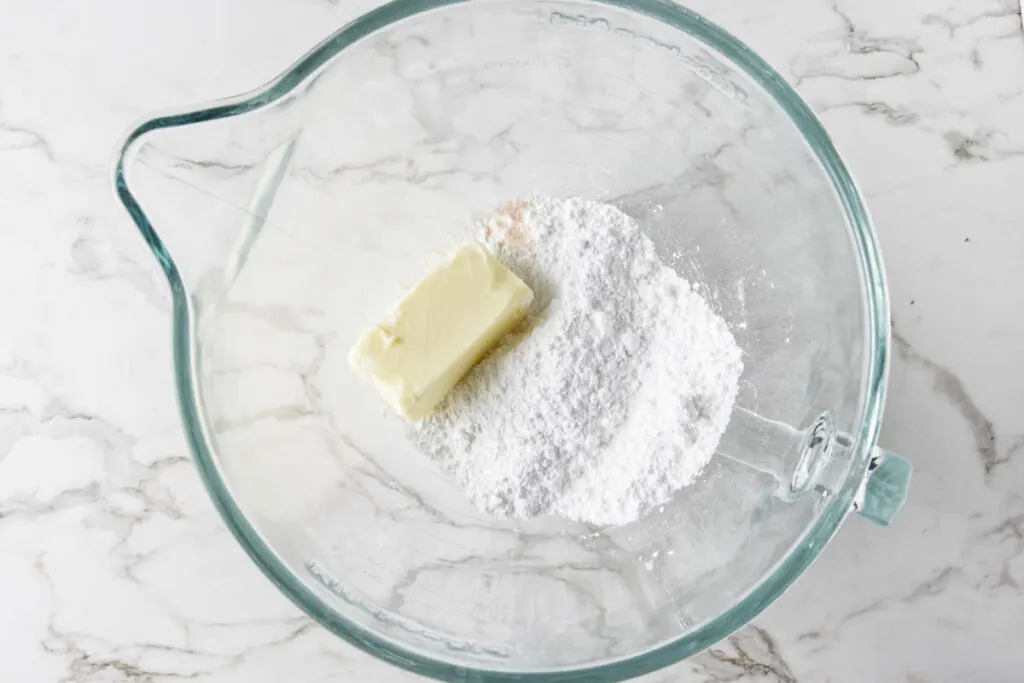 A stick of butter in a bowl with powdered sugar.