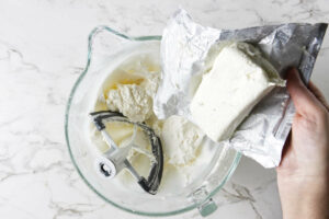 Adding cream cheese to a mixing bowl.