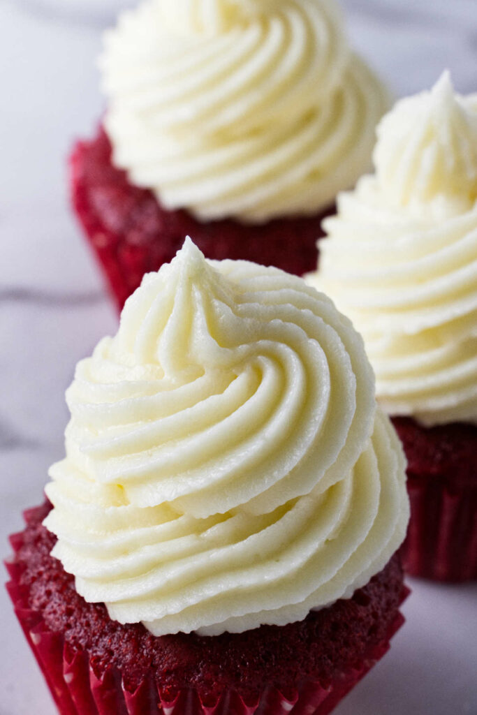 Three mini cupcakes topped with cream cheese frosting.