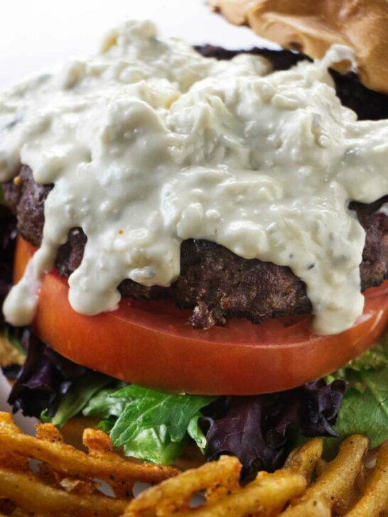 Blue cheese sauce drizzling down a burger.