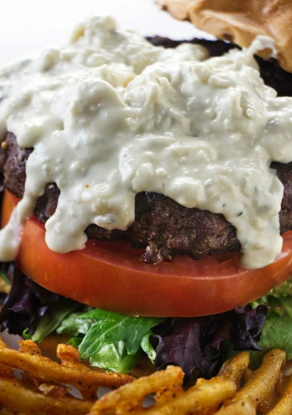 Blue cheese sauce drizzling down a burger.