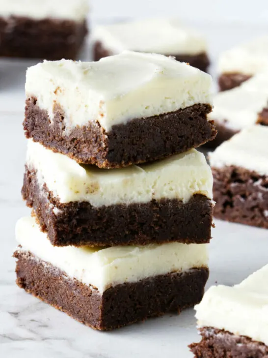 A stack of brownies with cream cheese frosting.