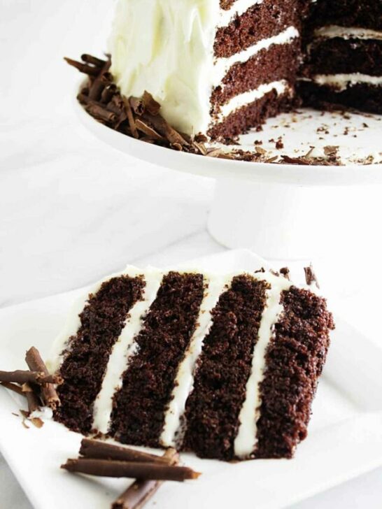 A slice of chocolate cake with cream cheese frosting.