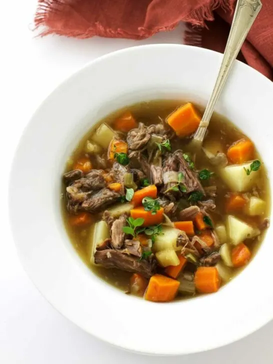 A bowl of oxtail soup with shredded oxtail meat and vegetables.