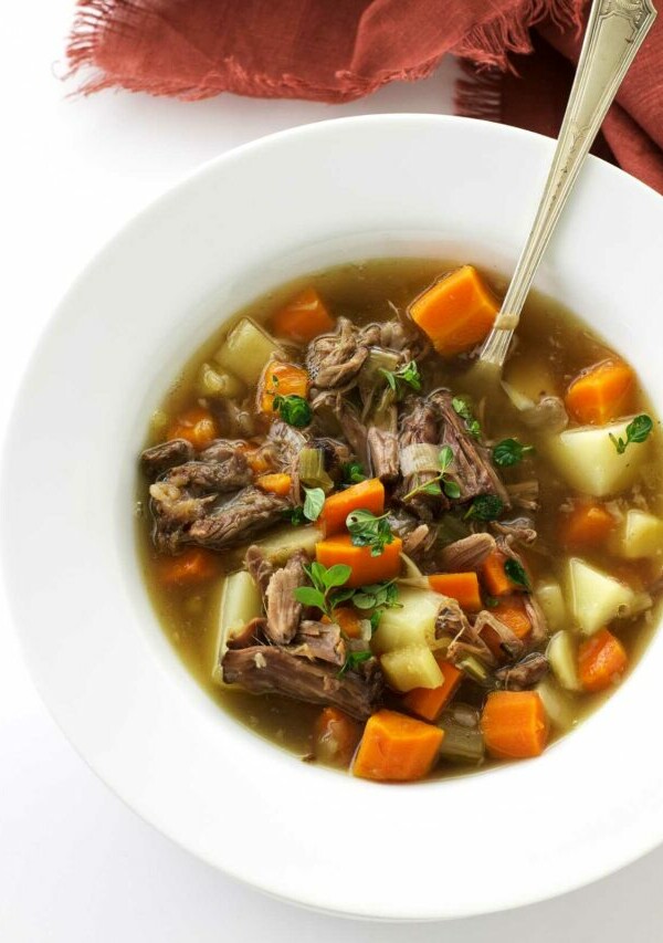 A bowl of oxtail soup with shredded oxtail meat and vegetables.