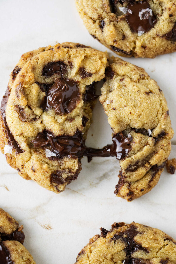 A warm chocolate chip cookie broken open to show gooey chocolate. 