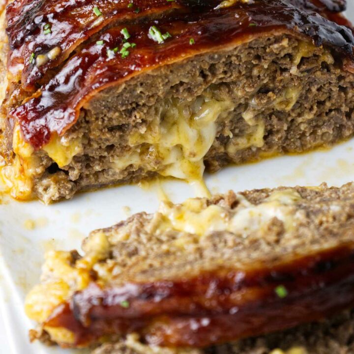 A slice of bacon wrapped smoked meatloaf on a plate.