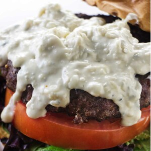 Blue cheese sauce drizzling down a steak burger.