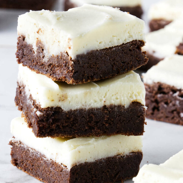 A stack of three brownies with cream cheese frosting.