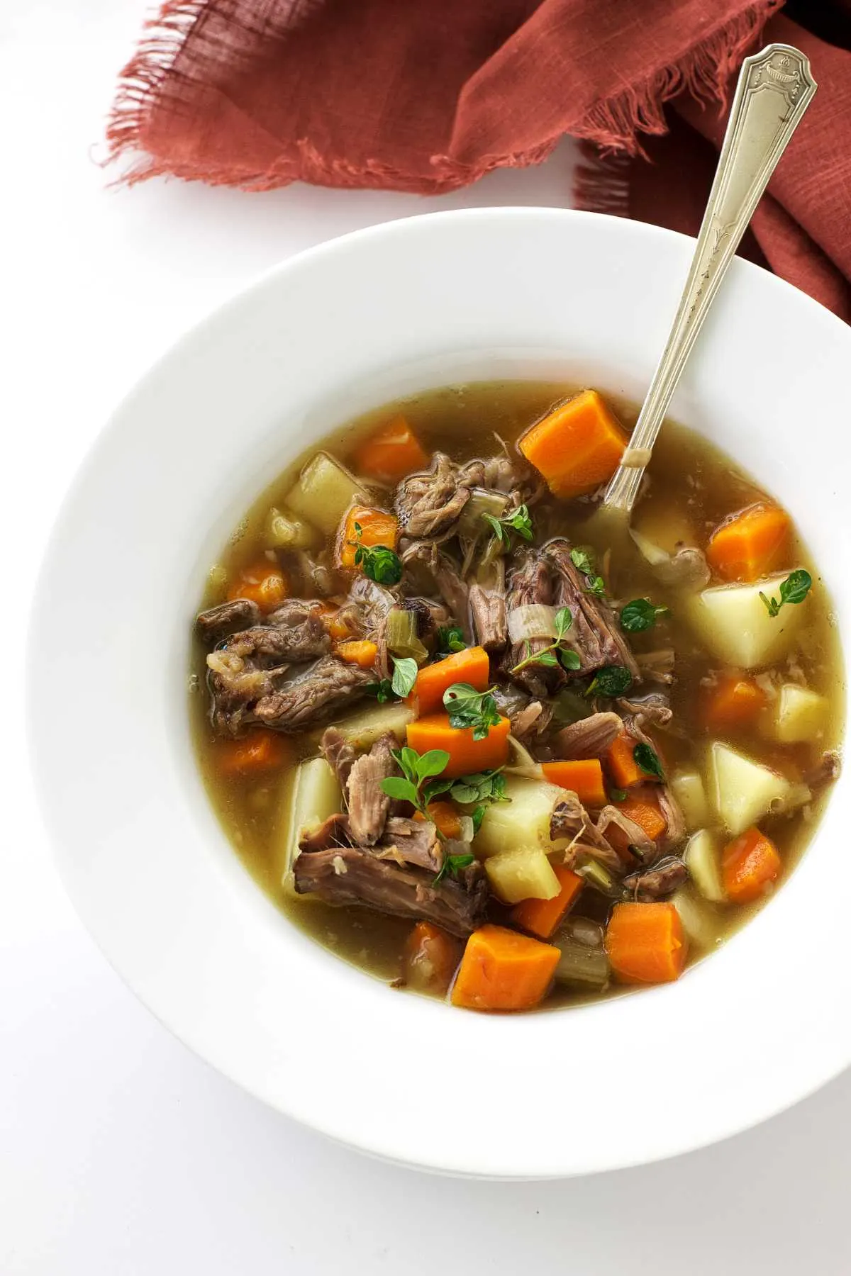 A bowl of oxtail soup with shredded oxtail meat and vegetables.