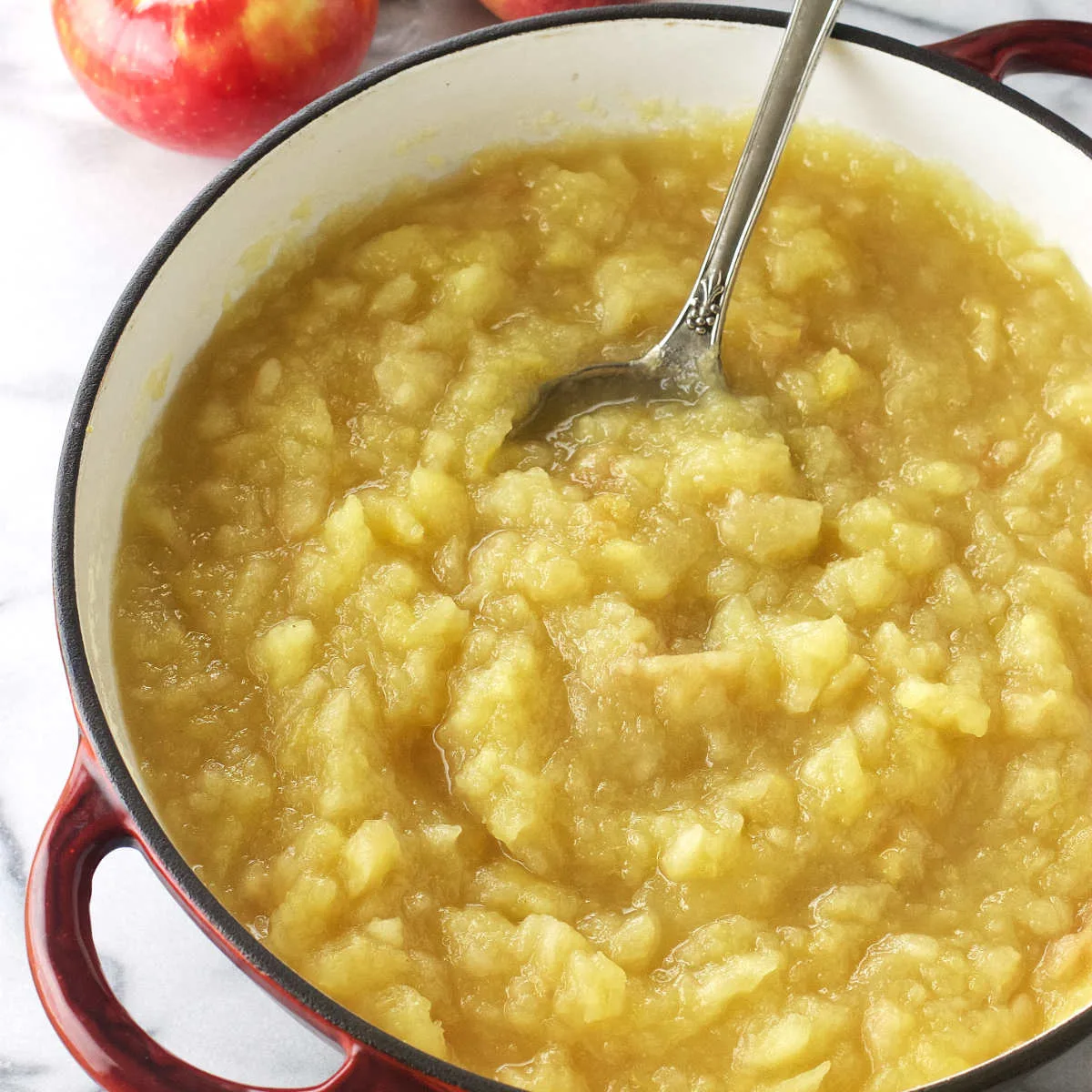 A pot of unsweetened applesauce with a serving spoon.