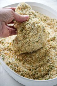 Coating chicken in panko breadcrumbs.