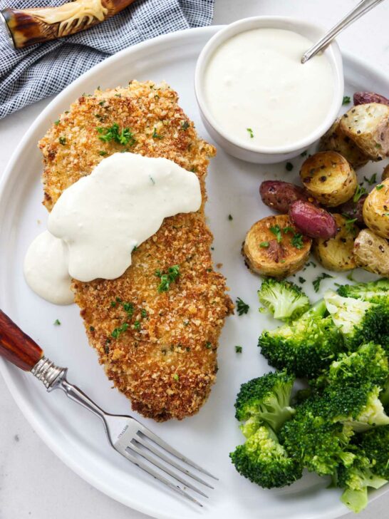 Panko crusted chicken on a plate with potatoes and broccoli.
