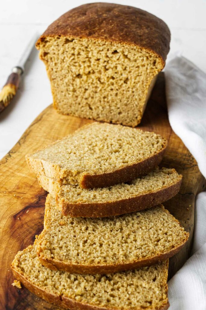 A loaf of whole grain einkorn bread sliced on a cutting board.