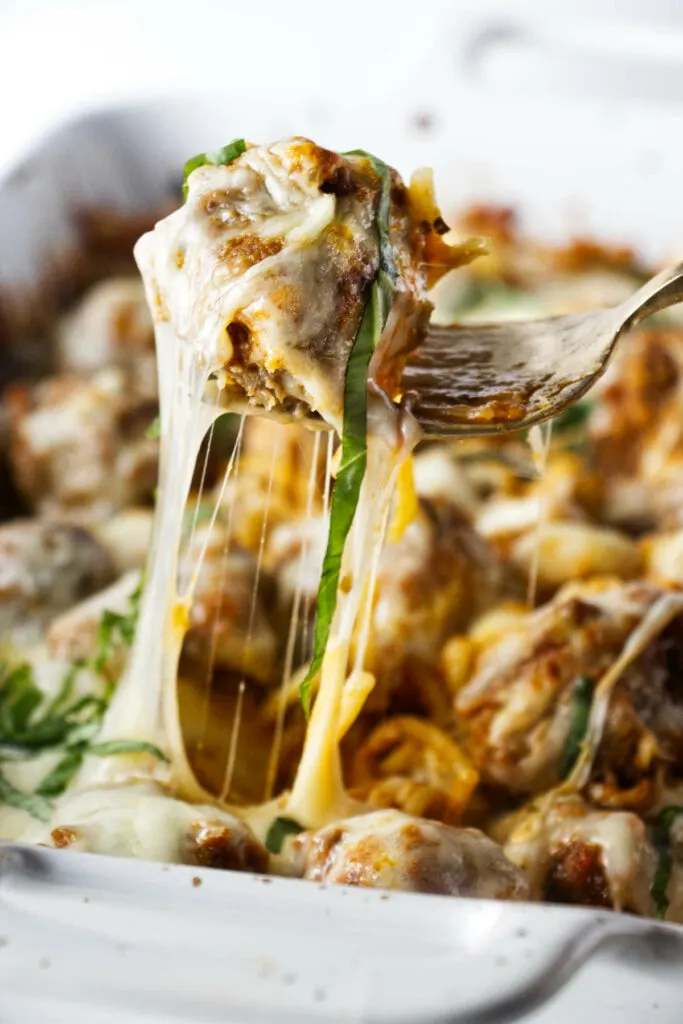 A meatball and stretchy, melted cheese from cheesy baked spaghetti casserole.