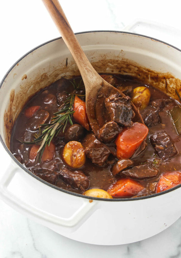 A wooden spoon in a Dutch oven with beef stew.