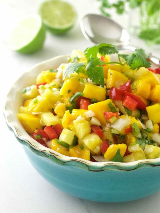 Pineapple mango salsa in a dish with limes in the background.