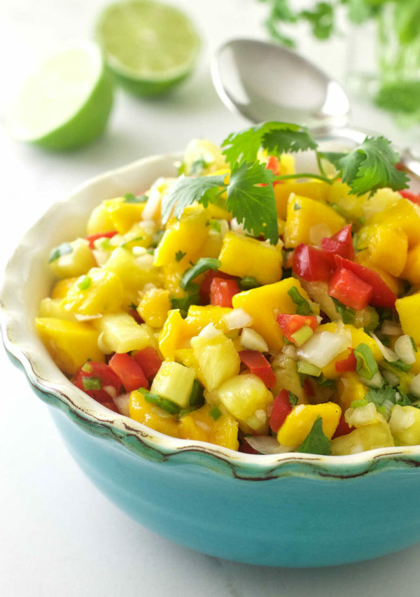 Pineapple mango salsa in a dish with limes in the background.