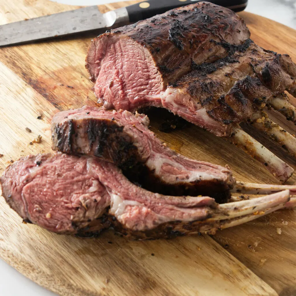 A grilled rack of lamb on a cutting board.