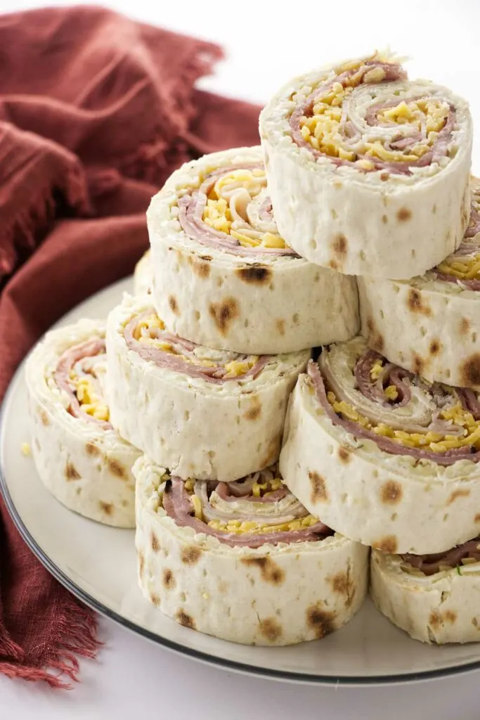 A stack of pinwheel sandwiches on a serving plate.