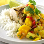 Grilled Mahi Mahi on a plate wth rice and mango salsa.