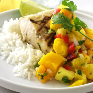 Grilled Mahi Mahi on a plate wth rice and mango salsa.