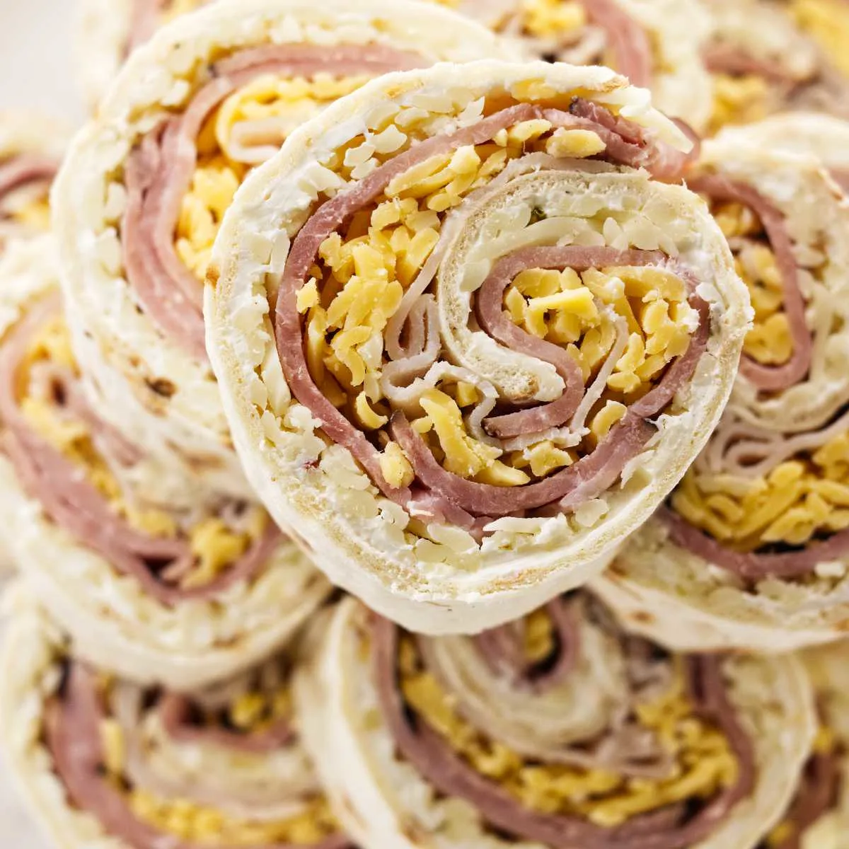 Ham and turkey pinwheels stacked on a plate.