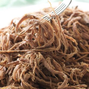 A slow cooker tri tip roast shredded with a fork.